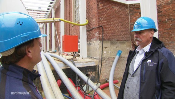 Zwei Männer mit blauem Helm auf einer Baustelle. © Screenshot 