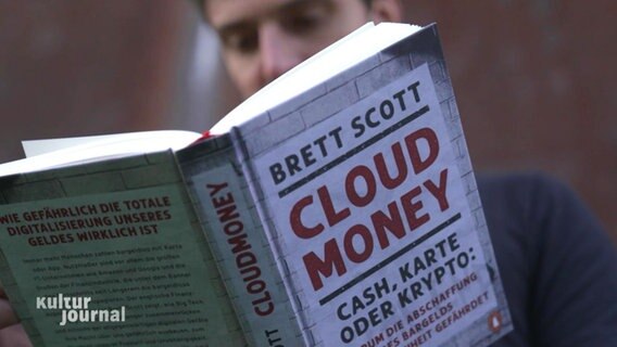 Jemand hält ein englischsprachiges Buch in der Hand. "Cloud Money" von Brett Scott. © Screenshot 
