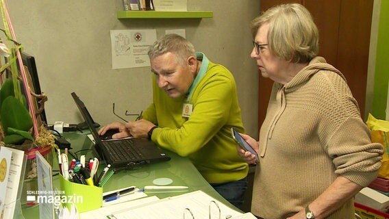Ein Mann und eine Frau stehen vor einem Computer. © Screenshot 