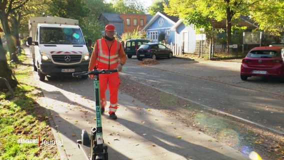 Ein Mitarbeiter der Stadtreinigung Hamburg geht auf einen auf einer Parkfläche abgestellten E-Scooter zu. © Screenshot 