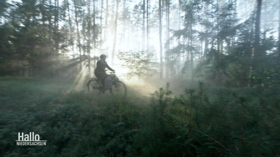 Eine Frau fährt mit einem Fahrrad durch das Lichtenmoor. © Screenshot 