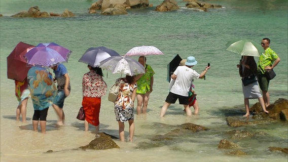 Touristen posieren an einem Strand. © Screenshot 