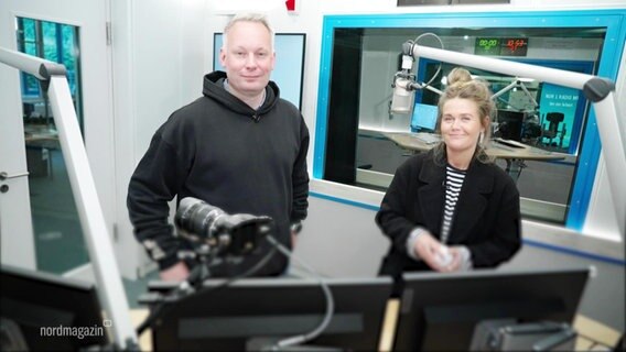 Ein Radiomoderator und eine Moderatorin stehen in einem Hörfunkstudio. © Screenshot 