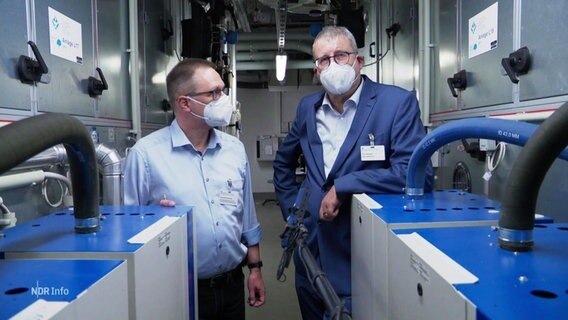 Zwei Männer stehen inmitten einer Klimaanlage eines Krankenhauses im Keller. © Screenshot 