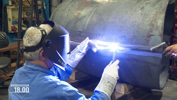 Ein Mann schweißt in einer Fabrik zwei Metallteile zusammen. © Screenshot 
