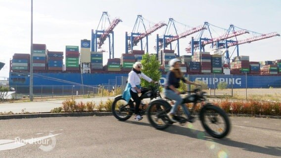 Radfahrer vor einem Containerschiff. © Screenshot 