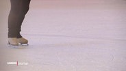 Zwei Füße, die in Schlittschuhen stecken, auf einer Eisbahn © Screenshot 
