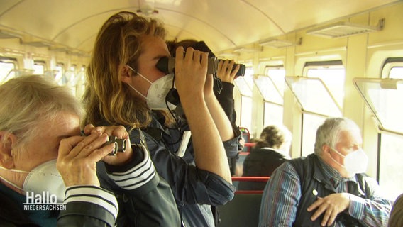 Besucher:innen des Zugvogel-Zugs schauen durch Ferngläser. © Screenshot 