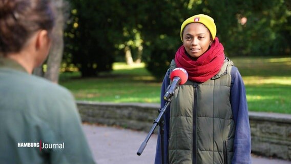 Eine Frau mit gelber Mütze und rotem Schal spricht in ein Mikrofon © Screenshot 