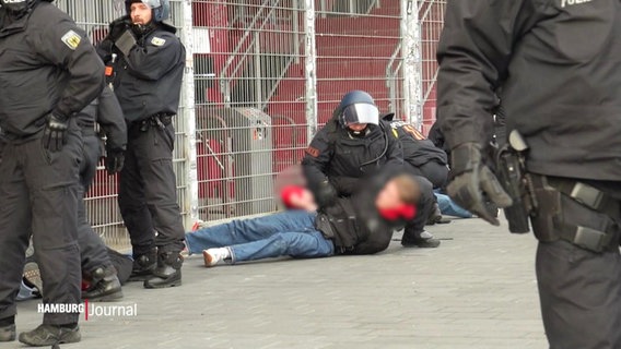 Ein Polizist stürzt sich gewaltvoll auf einen Fußballfan beim Hamburger Derby. © Screenshot 