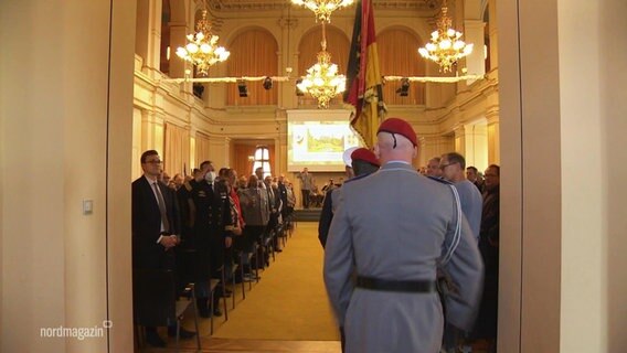 Fahnenträger der Bundeswehr beschreiten einen Festsaal. © Screenshot 