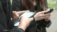Zwei Schülerinen halten ihr Smartphone in den Händen. © Screenshot 