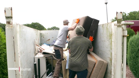 Zwei Männer entsorgen Möbel in einem Container bei einer Haushaltsauflösung. © Screenshot 