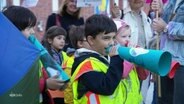 Kinder halten sich beim Sprach-Kita Protesten Papierröhren vor die Münder. © Screenshot 