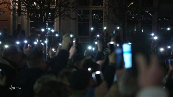 Protestierende benutzen ihre Smartphones als Lichter im Dunkeln. © Screenshot 