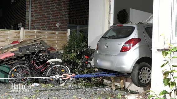 Ein zerstörtes Auto wird aus einem Haus gezogen. © Screenshot 
