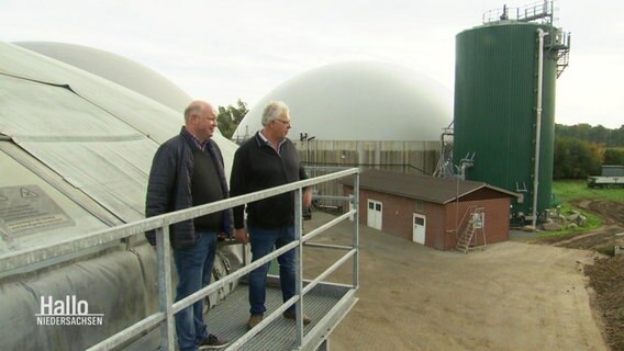 Zwei Männer stehen auf dem Geländer eines größeren Biogas-Kraftwerks. © Screenshot 