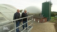 Zwei Männer stehen auf dem Geländer eines größeren Biogas-Kraftwerks. © Screenshot 