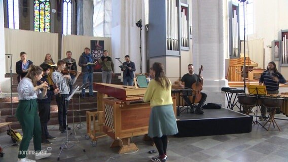 In einer Kirche musizieren viele Menschen mit barocken Musikinstrumenten. © Screenshot 