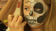 Ein Mädchen wird als Skelett geschminkt © Screenshot 