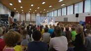 Schülerinnen und Schüler verfolgen das musikalische Theaterstück. © Screenshot 