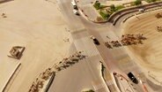 Aufnahme von oben: Dutzende Kamele überqueren eine Straße in Katar. © Screenshot 