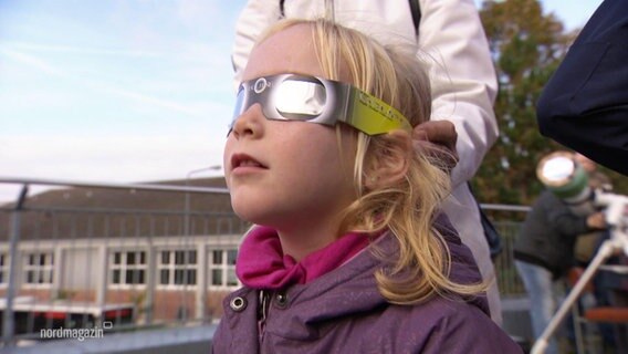 Ein junges Mädchen betrachtet das Naturereignis durch eine Schutzbrille. © Screenshot 