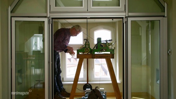 Uhrenmacher Helmut Langer wartet eine 150 Jahre alte Turmuhr im Rathaus Laage. © Screenshot 