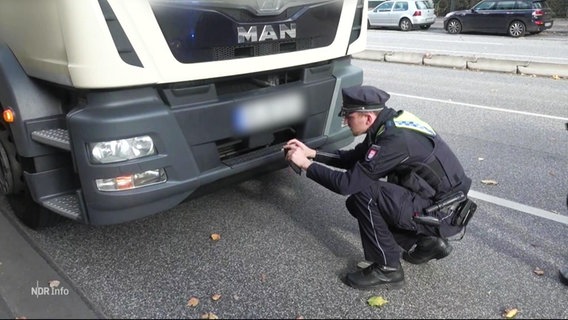Ein Polizeibeamter untersucht einen Lastwagen. © Screenshot 