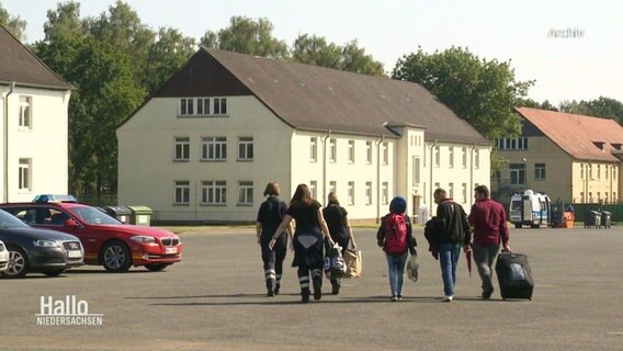 Ankommende Flüchtlinge gehen auf ein Gebäude zu. © Screenshot 