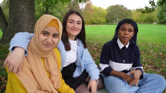 Annabel, Heba und Sima sitzen in einem Park auf einer Decke. © Screenshot 