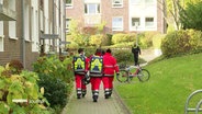 Rettungskräfte laufen in eine Wohngegend. © Screenshot 