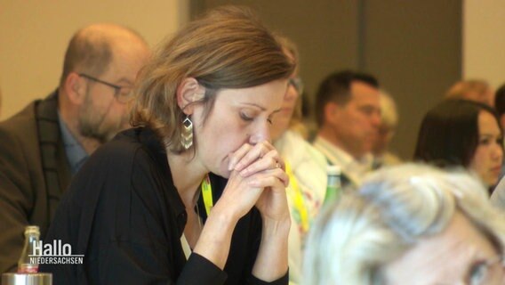 Auf einem FDP-Parteitag stützt eine Delegierte ihren Kopf auf die gefalteten Hände. © Screenshot 