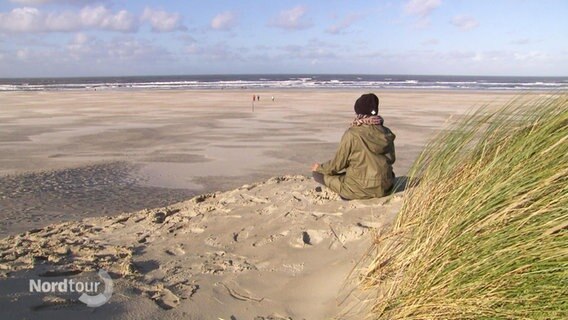 Eine Frau meditiert am Strand. © Screenshot 