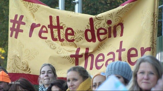 "Rette dein Theater", steht auf einem Banner von Protestierenden. © Screenshot 