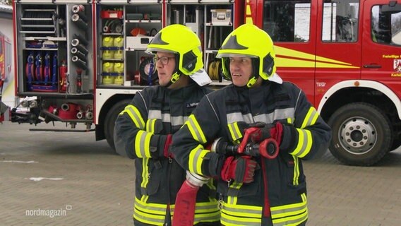 Zwei Feuerwehrmenschen halten einen Schlauch. © Screenshot 