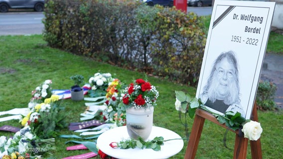 Ein Bild und die Urne des verstorbenen Intendanten Wolfgang Bordel mit vielen Blumen die zum Abschied in Anklam niedergelegt wurden. © Screenshot 
