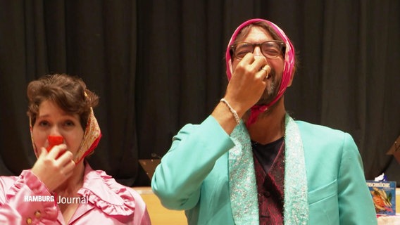 Ein Mann und eine Frau spielen lachend auf Nasenflöten © Screenshot 