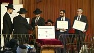 Mehrere Rabbiner stehen auf einer Bühne und werden ausgezeichnet. © Screenshot 