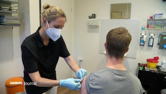 Eine Ärztin impft einen Patienten in einer Praxis. © Screenshot 
