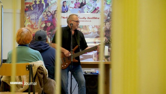Ein Mann spielt E-Gitarre vor einem Publikum. © Screenshot 