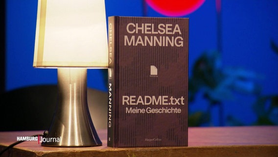 Ein Buch von Chelsea Manning steht auf einem Tisch neben einer Lampe. © Screenshot 