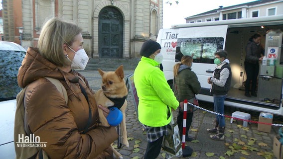Mehrere Menschen stehen mit ihren Hunden vor einer mobilen Tierarztpraxis. © Screenshot 