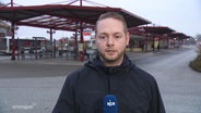 Ein NDR Reporter steht vor einem Busbahnhof. © Screenshot 