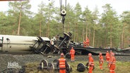 Mit einem Kran bergen Rettungskräfte Teile eines zerstörten Zuges. © Screenshot 