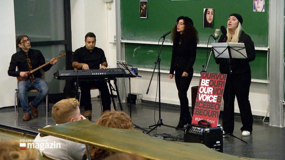 Eine Gruppe Musiker performen während einer Kundgebung als Protest gegen das Iran-Regime an einer Kieler Universität. © Screenshot 