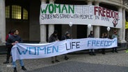 Demonstrierende Studierende halten bei Protesten gegen das Iran-Regime an der Universität Hamburg einen "Woman Life Freedom" Banner hoch. © Screenshot 