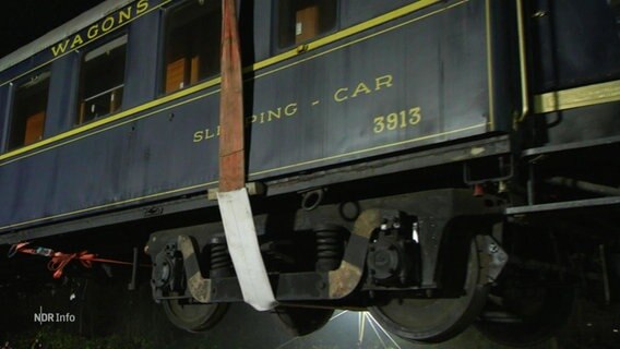 Ein Reisezug-Wagon hängt an einem Kran. © Screenshot 