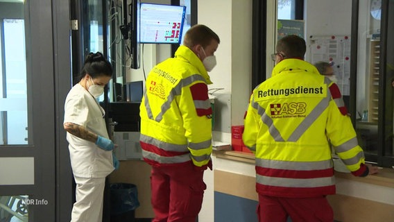 Zwei Rettungssanitäter und eine Krankenschwester stehen in einem Krankenhaus. © Screenshot 