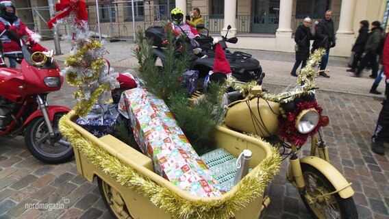 Ein weihnachtlich geschmücktes Motorrad, auf dessen Beifahrersitz ein Geschenk und ein kleiner Tannenbaum stehen. © Screenshot 